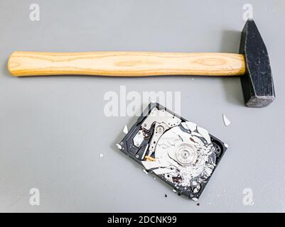 Piatto frantumato nel disco rigido del computer e un martello. Foto Stock