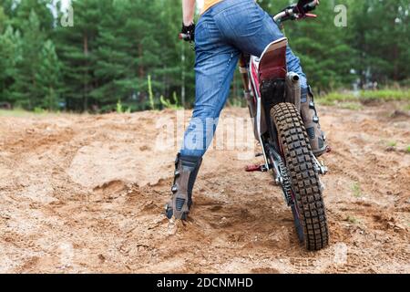 Uomo adulto che corre su pista sabbiosa con la sua moto a croce, vista posteriore, spazio di copia Foto Stock