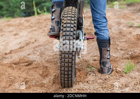 Motocicletta maschile pilota ha un giro in sabbia buca, vista posteriore di pneumatico e stivali da uomo Foto Stock