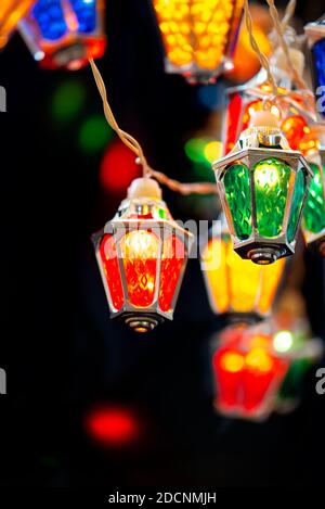 Luci natalizie scintillanti di notte nera. Colorate luci natalizie fairy con lampade a forma di lanterna d'epoca. Foto Stock