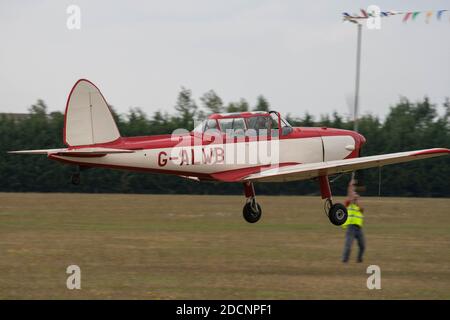 Un motore singolo De Havilland DHC 1 Chipmunk al White Waltham Airfield. Acrobazie che vola a basso livello sotto un 'arco' tenuto da due uomini. Foto Stock