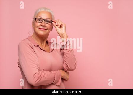 Donna anziana sorridente che indossa la vista sorridendo guardando la fotocamera. Scatto in studio Foto Stock