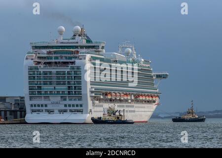 la nave da crociera azura che lascia il porto di southampton attracca con due rimorchiatori che aiutano a tirare la nave dall'ormeggio o dal molo. Foto Stock