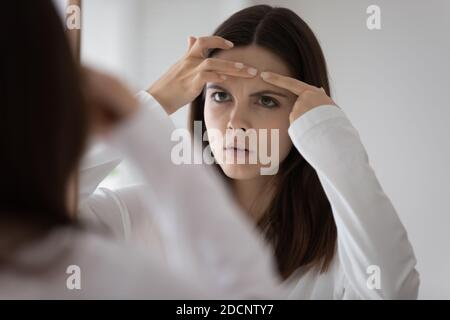 Preoccupata giovane donna seccata di cattivo stato della pelle del viso Foto Stock