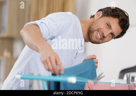 uomo che mette il lavaggio sopra a cavallo vestiti indoor Foto Stock