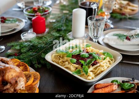 Tavolo festivo servito con pasta, tacchino arrosto, piatti, candele e altro Foto Stock