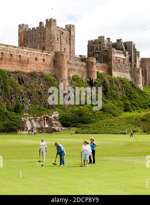 Bamburgh, Northumberland, Inghilterra - 16 luglio 2020: Gioco tradizionale inglese di croquet giocato con lo sfondo del Castello di Bamburgh, Northumberland. Foto Stock