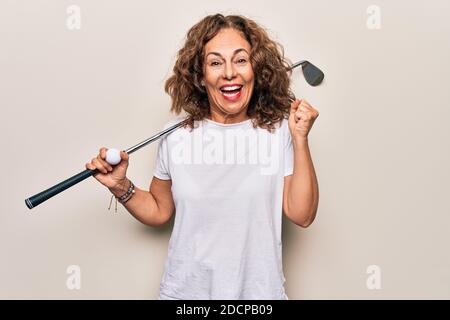 Media età bella sportswoman giocare a golf utilizzando bastone e palla su sfondo bianco urlando orgoglioso, celebrando la vittoria e il successo molto eccitato Foto Stock