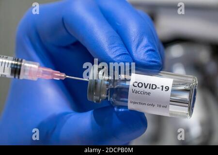 Il medico o lo scienziato sta tenendo in mano il vaccino COVID-19. Foto Stock