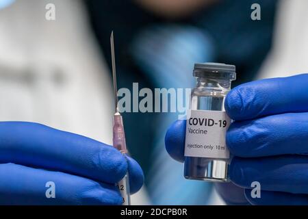 Il medico o lo scienziato sta tenendo in mano il vaccino COVID-19. Foto Stock