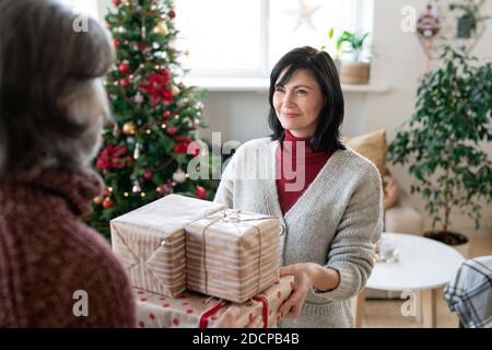 Felice donna matura che dà i regali imballati di Natale al suo marito Foto Stock