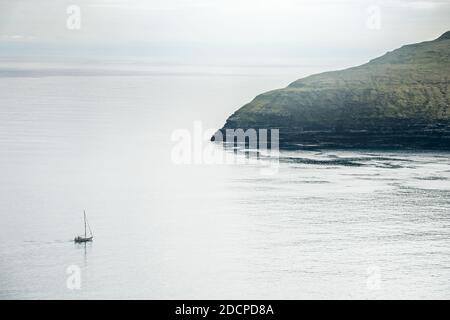 Vista aerea della barca a vela che galleggia sul mare increspato verso roccioso costa in giornata Foto Stock