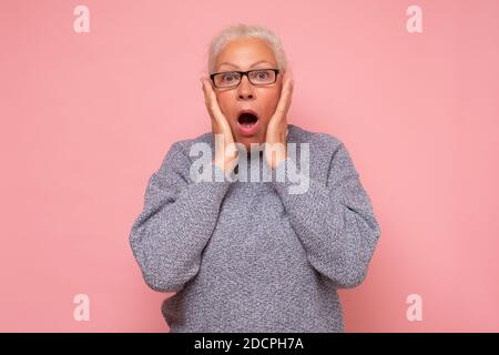 Stressato sorpresa vecchia donna matura guardando la macchina fotografica preoccupata per le rughe facciali. Foto Stock