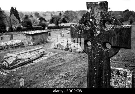 Primo piano di croce celtica in una parrocchia del Vecchio mondo Cimitero presso la chiesa di St Michael & All Angels con vista su un Paesaggio ondulato della campagna inglese Foto Stock