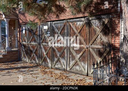 Brooklyn, NY - Novembre 14 2020: Porte di garage in legno intemperie, per un garage di tre auto, adiacente ad una casa a Greenpoint, Brooklyn, New York. La struttura i Foto Stock