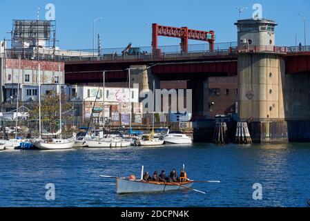 Queens, NY - Novembre 14 2020: Sei persone fila uno skiff di 28 piedi a Newtown Creek, Queens, New York. Dietro la barca a remi si trova il ponte Pulaski che prende la veicolare Foto Stock