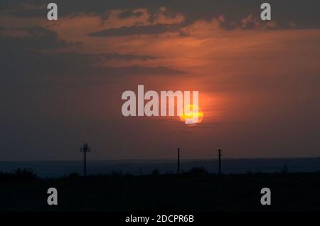 L'antenna è un trasmettitore cellulare e una linea di fili sullo sfondo di un tramonto rosa e di un cielo blu. Foto Stock
