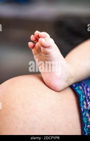 Primo piano astratto delle dita dei piedi del bambino che riposano sul suo grembo delle madri. Foto Stock