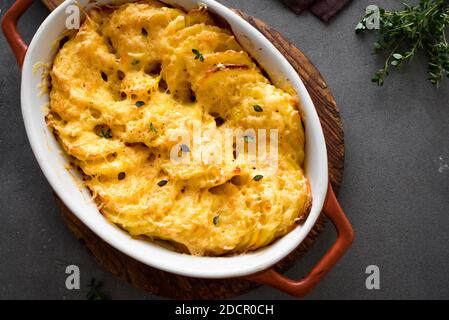 Gratin di patate. Casseruola di patate appena sfornata su tavolo scuro, vista dall'alto, primo piano. Foto Stock