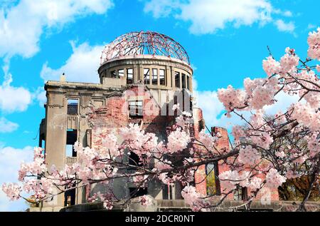 Stagione dei ciliegi in fiore in Giappone. Alberi in fiore sakura vicino alla cupola della bomba atomica (Genbaku Dome Mae), Hiroshima Peace Memorial, Giappone. Rovine di un buil Foto Stock