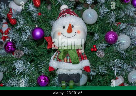 Decorazione di Natale. Un pupazzo di neve con gli sci davanti ad un albero di Natale Foto Stock
