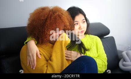Triste donna nera afroamericana che ottiene il sostegno dalla sua ragazza asiatica. Amicizia e relazione e salute mentale. Foto di alta qualità Foto Stock