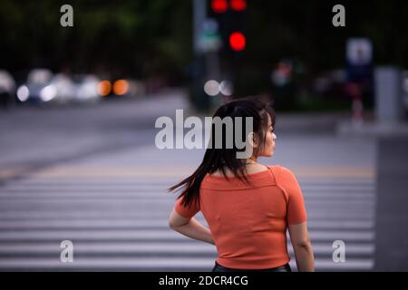 Huzhou, Cina 2020 settembre 28: Ritratto di felice ragazza asiatica piace viaggiare in città in estate girato da dietro. Donna che cammina durante Foto Stock