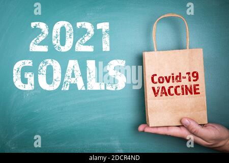 2021 obiettivi. Vaccino Covid-19. Borsa regalo di carta in mano di un uomo. Foto Stock