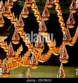 Vista ravvicinata delle gocce di bronzo sospese che sono parte di una installazione dinamica cinetica di arte della pioggia Foto Stock