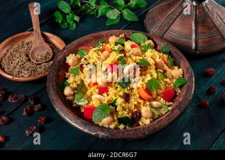 Couscous africano nella tagine, con spezie ed erbe su uno sfondo di legno scuro Foto Stock