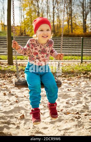 Carino bambina su un'oscillazione in un parco giochi Foto Stock