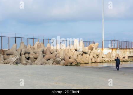 Un gruppo di grandi frangiflutti in cemento si trovano sulla riva vicino al molo. Foto Stock