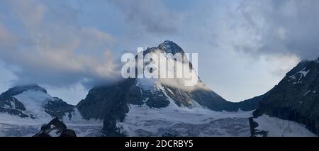 Foto panoramica di Dent Blanche nelle Alpi svizzere, leggermente coperto di nuvole, molta neve ai piedi Foto Stock
