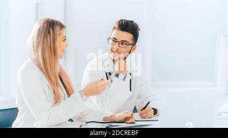 I colleghi medici parlano seduti ad un tavolo in ufficio Foto Stock