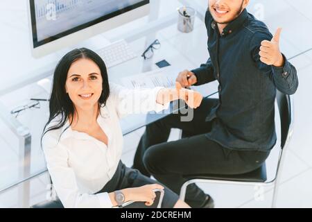 Vista dall'alto. Due dipendenti seduti alla scrivania e con i pollici Foto Stock