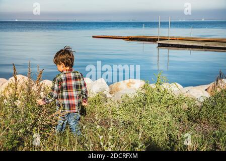 Un bambino, un bambino o un bambino al mare porta l'infanzia e scopre la bellezza della natura guadagnando il desiderio, imparando la vita e alimentando la sua curiosità Foto Stock