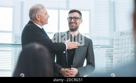 Project Manager si congratula con il miglior dipendente durante una riunione con il gruppo di lavoro. Foto Stock