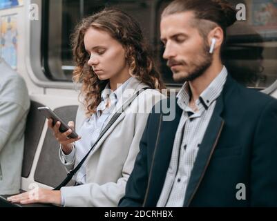 passeggeri con smartphone seduti in un'auto della metropolitana. Foto Stock