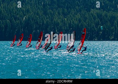 Un gruppo di surfisti del vento con vele rosse sta navigando sul Lago Silvaplana. Foto Stock