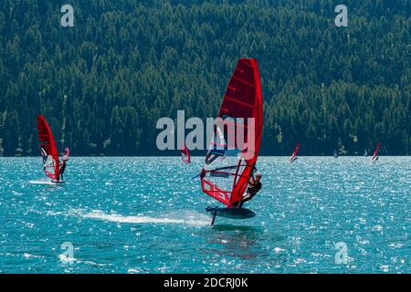 I surfisti del vento con vele rosse navigano sul Lago Silvaplana. Foto Stock