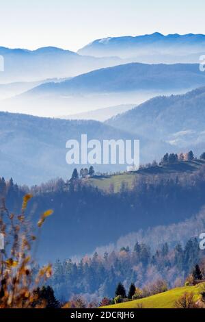 Bella vista di valli nebbie, foreste e colline in autunno dall'alta posizione in Slovenia. Turismo, escursionismo, natura, ambiente e silvicoltura concetto Foto Stock