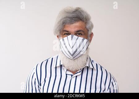 Maschio di media età che indossa una maschera. Sfondo bianco. Scatto in studio. Guardando la fotocamera Foto Stock