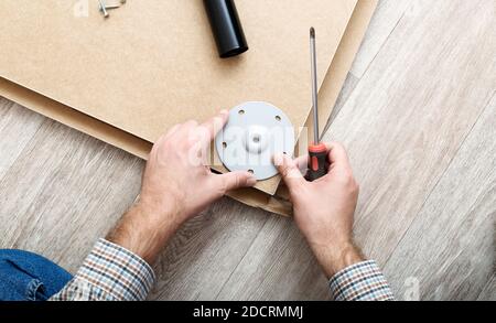 Montaggio di mobili con un cacciavite. Il padrone delle mani maschili raccoglie i mobili usando gli attrezzi del cacciavite, lo strumento a casa. In movimento, miglioramento domestico Foto Stock