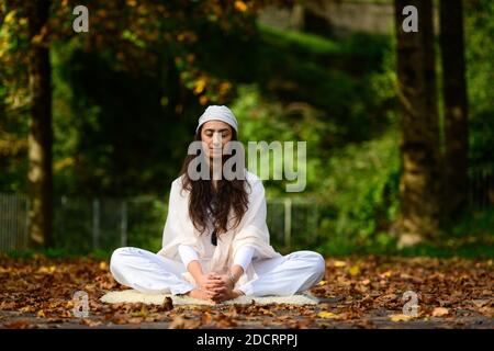 Donna in bianco in autunno parco mentre facendo yoga Foto Stock