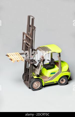 Modello giocattolo di un movimentatore telescopico industriale, caricatore di pallet, carrello elevatore di colore verde chiaro su sfondo grigio chiaro, fuoco selettivo, spazio di copia. Foto Stock