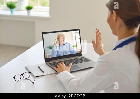 Sorridente anziano uomo anziano paziente saluto professionale donna medico online durante una riunione a distanza Foto Stock