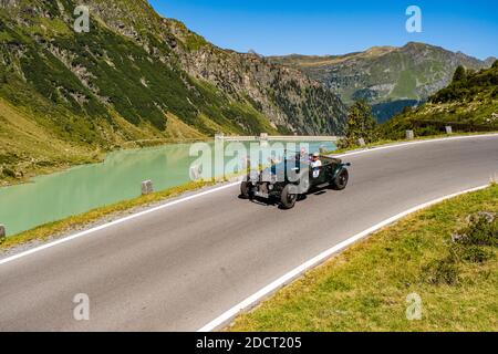 Un'auto d'epoca BENTLEY 3 DA 1/2 LITRI VAN DEN PLAS che passa accanto a un lago sulla Silvretta Hochalpenstrasse durante il Rally di Arlberg Classic Car. Foto Stock