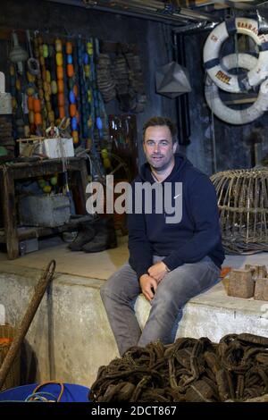 Inghilterra / Cornovaglia / St. Ives / artista Sam Bassett in posa nella cantina sotto gli studi di artisti dove i pescatori fissare reti su Porthmeor Beach . Foto Stock