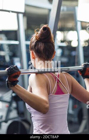 Giovane donna che fa squat con barbell in palestra Foto Stock