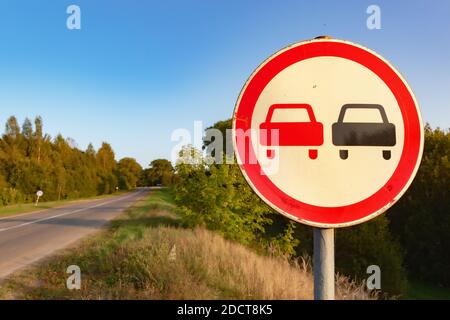 Segnale stradale che impedisce il sorpasso sul lato della strada Foto Stock